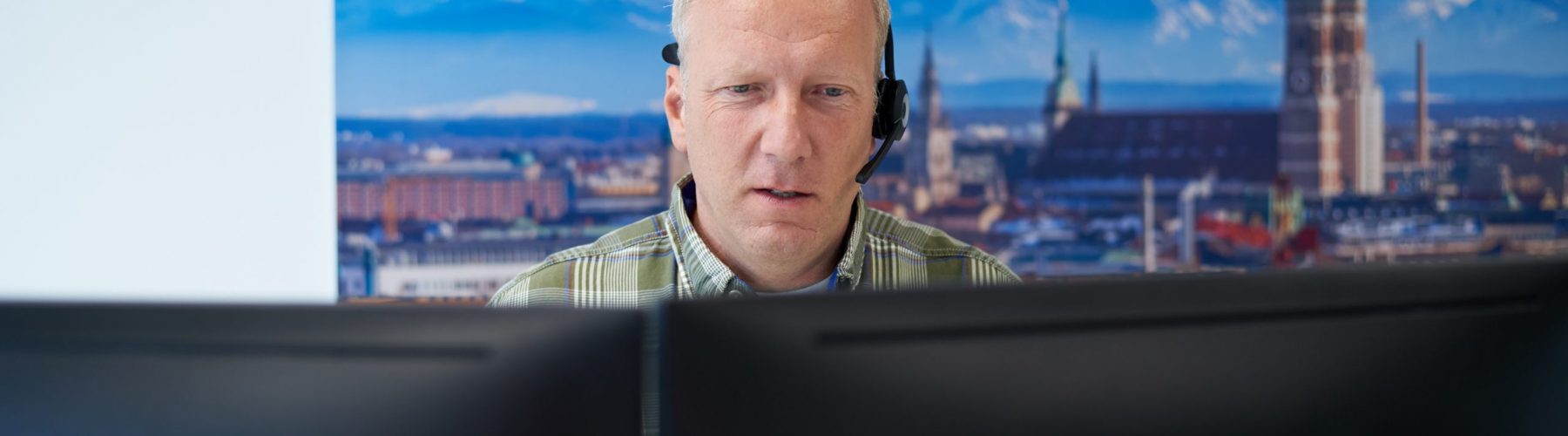 Foto eines Mannes während er an einem Schreibtisch sitzt und am PC arbeitet