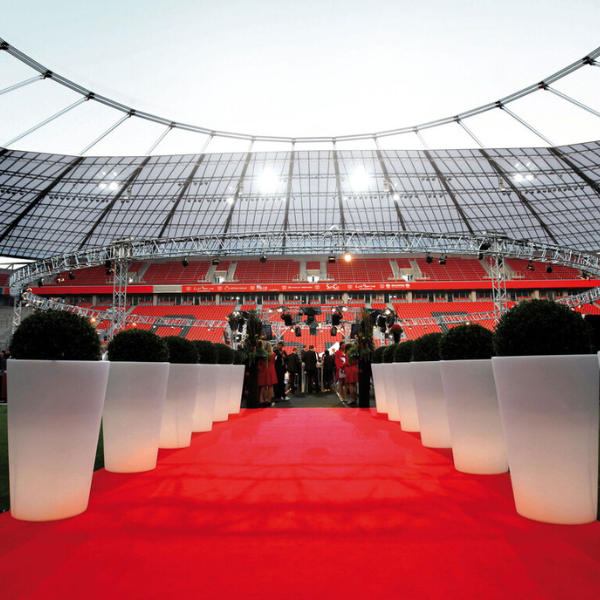 a red carpet with white vases in front of a stadium