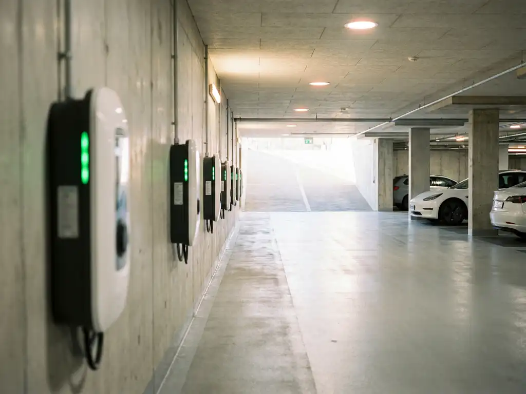 EV-Ladestationen mit grünen Statuslichtern in einem modernen Tiefgaragenparkhaus eines Gewerbegebäudes.